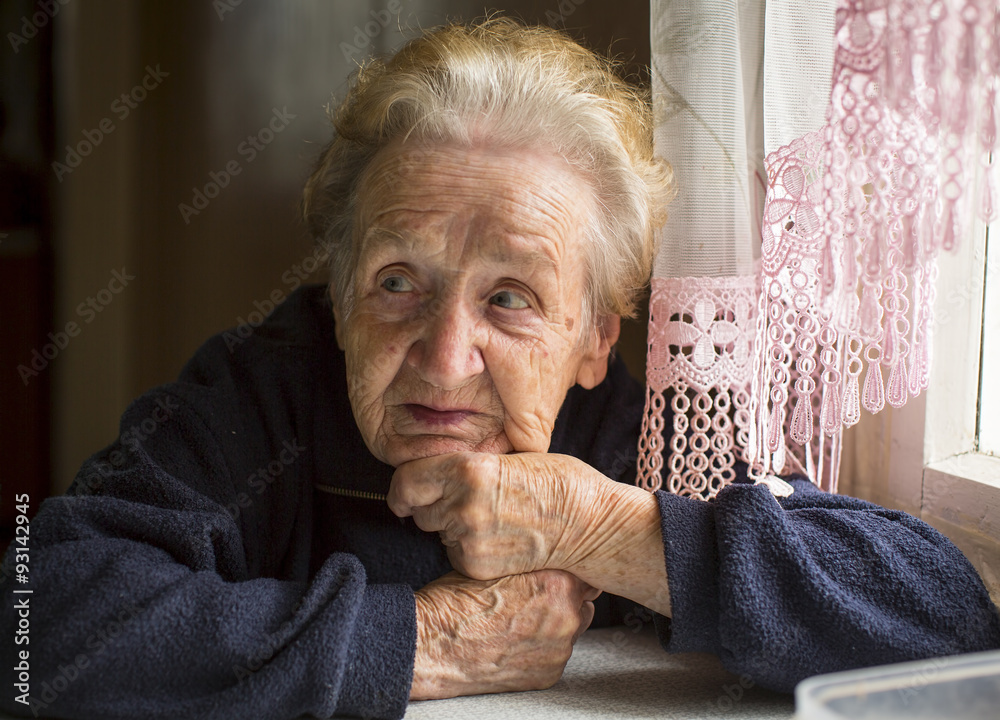 Elderly woman sitting at table in the house. Elderly woman sitting at table in the house.