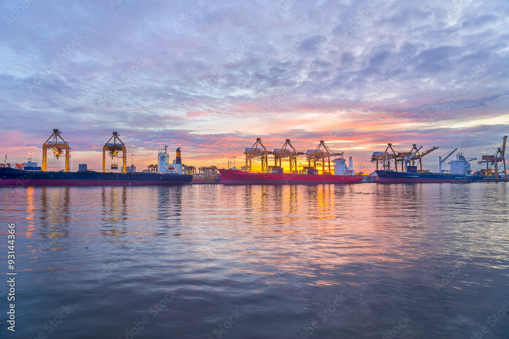 Cargo ship and crane at port reflect on river, twilight time