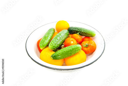 tomatoes and cucumbers on a dish on white