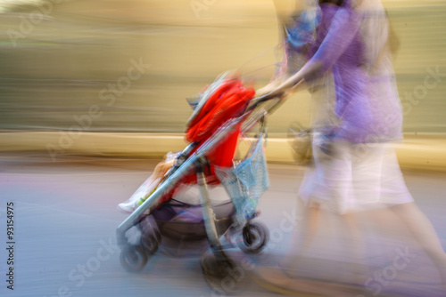 Fotografie Mom rushes through town with a blurred stroller late for, what?