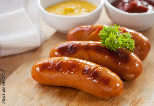 grilled sausage on wooden block serve with mustard and ketchup