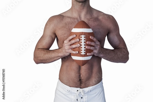 Midsection of shirtless rugby player holding ball