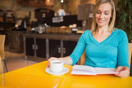 Young woman holding book with coffee cup