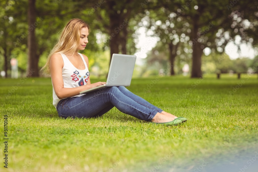 Full length of confident woman using laptop at park Full length of confident woman using laptop at park