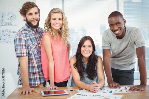 Portrait of happy woman with coworkers at desk 