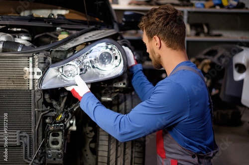 Mechanic with new car headlight in a workshop