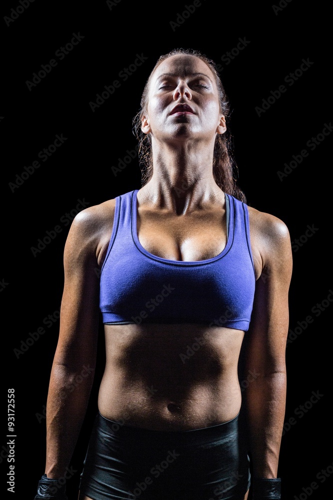 Fit woman meditating against black background Fit woman meditating against black background