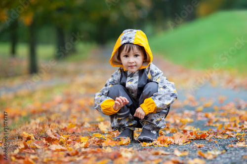 Little boy, playing in the rain in autumn park