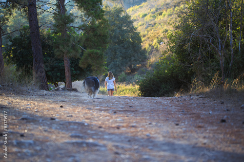 Young girl with collie dog walking in the forest.