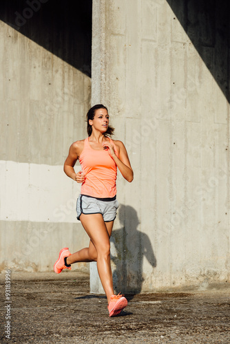 Sporty cheerful woman running and training outdoor. Female runner exercising.