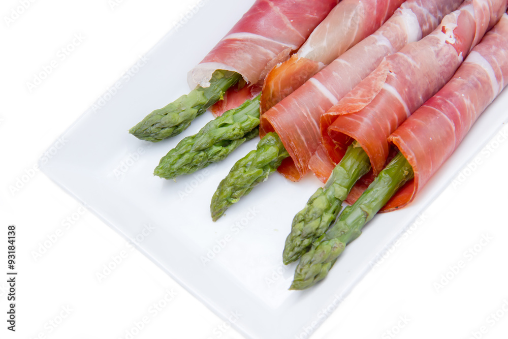 Asparagus and ham on the tray on white background seen up close Asparagus and ham on the tray on white background seen up close