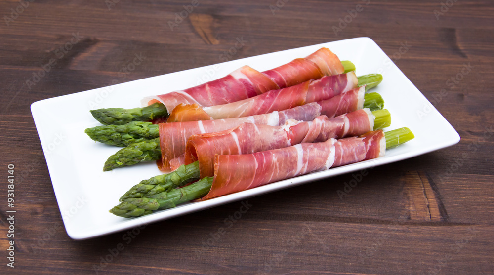 Asparagus and ham on tray on wooden table