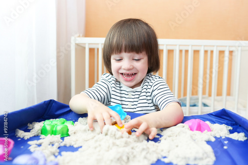Happy boy plays kinetic sand at home
