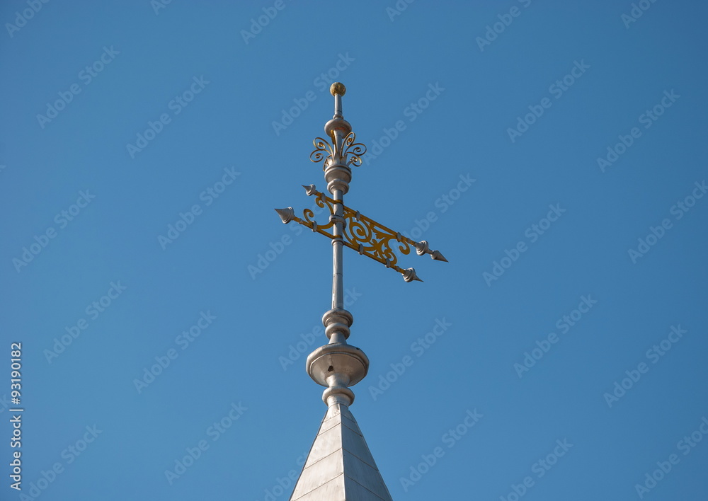 Vintage gilded weathervane - flag on the tower against the blue sky