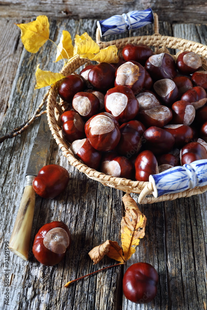 Chestnuts in wicker basket and autumn leaves Chestnuts in wicker basket and autumn leaves