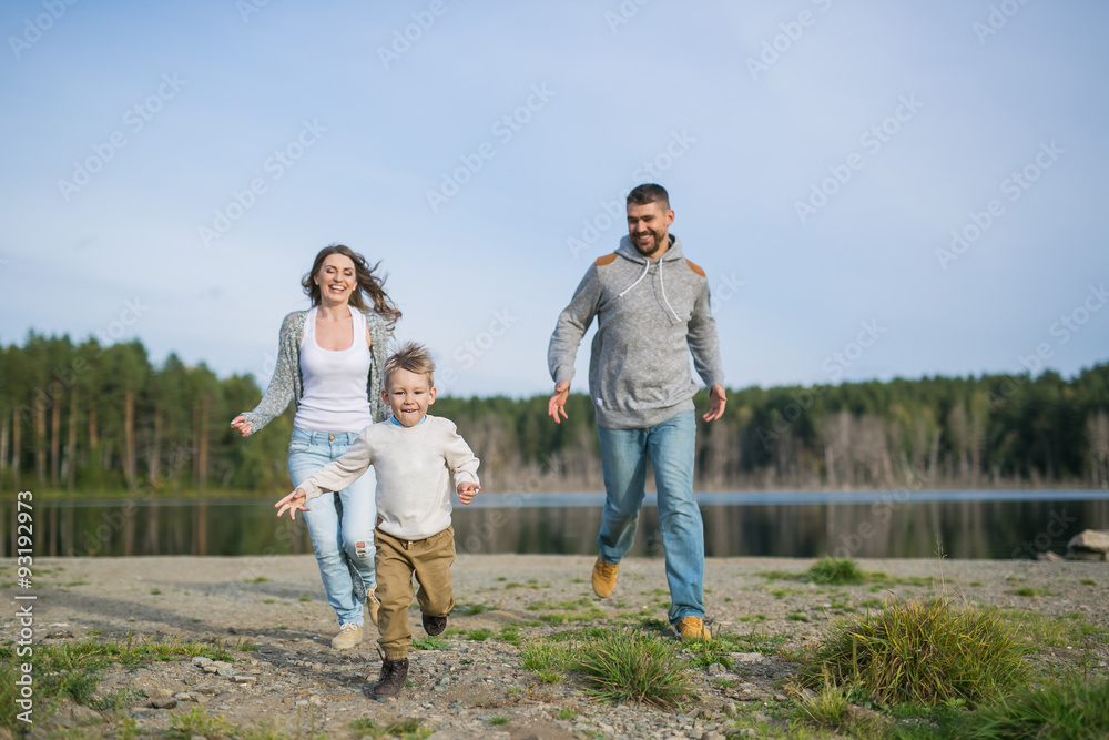 Fototapeta premium A young parents run behind their son on a coast