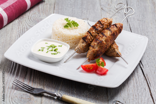 Barbecued kofta - kebeb with rice and vegetables on a plate.