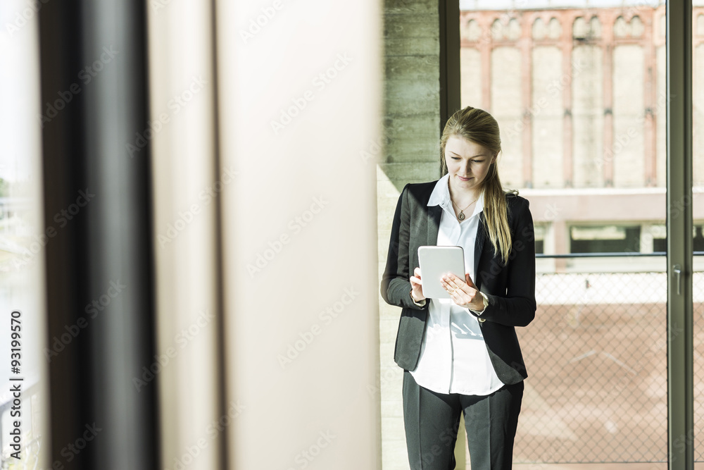 Young businesswoman at the window looking on digital tablet Young businesswoman at the window looking on digital tablet