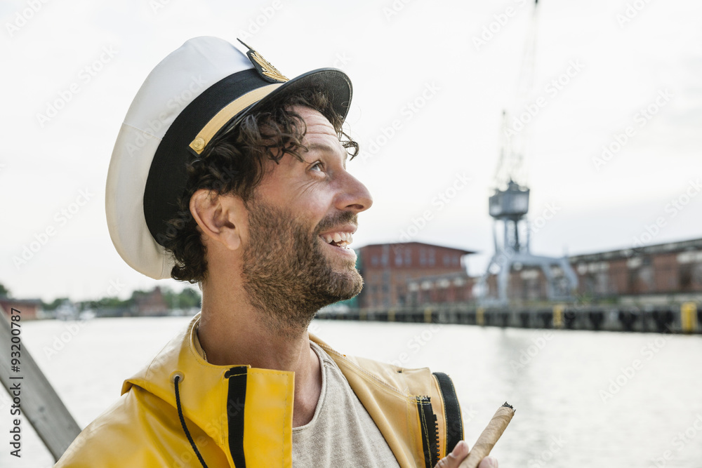 Smiling man wearing rain coat and captain's hat at the waterside Stock  Photo | Adobe Stock