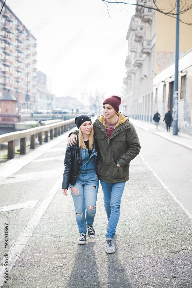 young beautiful couple lovers walking in the city hugging, she i