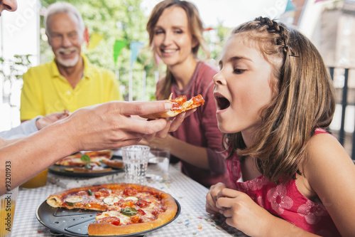 Girl being fed with homemade pizza at family party