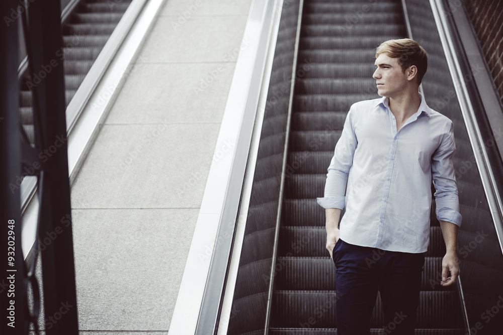 Young man standing on escalator Young man standing on escalator