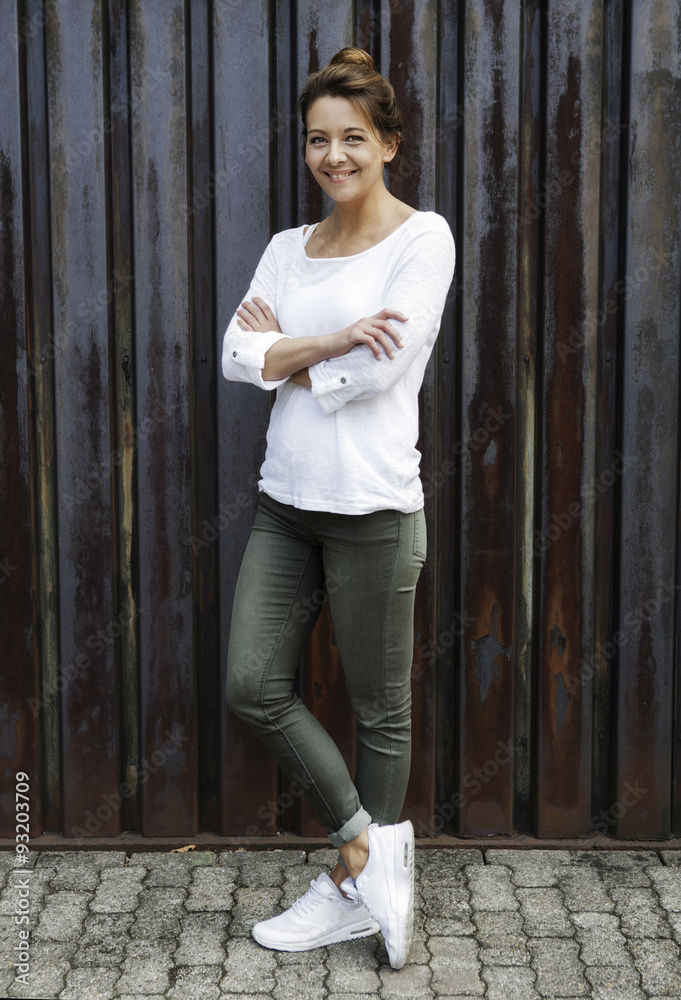 Portrait of smiling woman standing in front of rusty metal wall Portrait of smiling woman standing in front of rusty metal wall