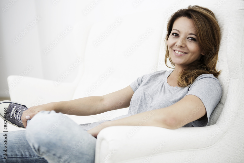 Portrait of smiling woman sitting on white couch Portrait of smiling woman sitting on white couch
