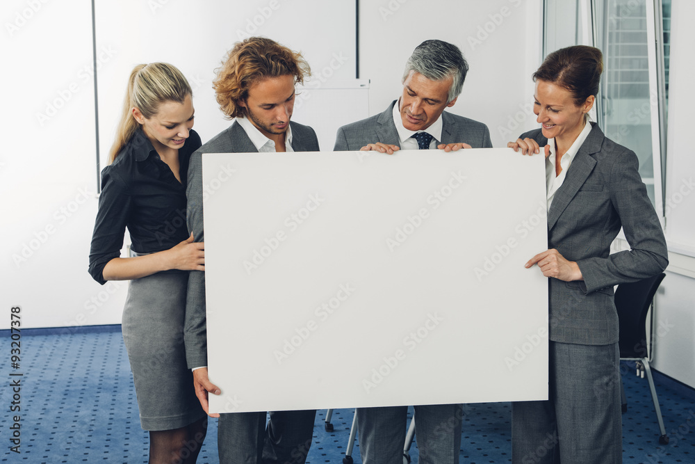 Portrait of happy business team holding a blank billboard while at office Portrait of happy business team holding a blank billboard while at office
