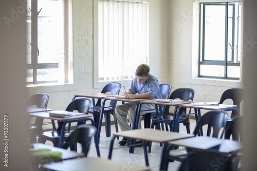 Schoolboy writing in classroom photo
