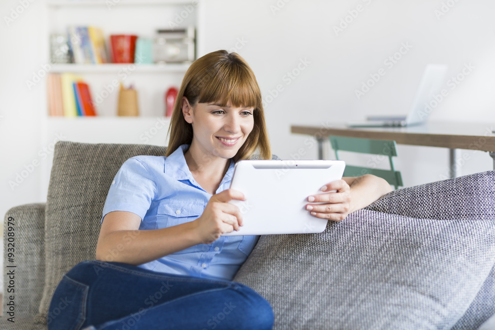 Pretty female using tablet pc computer at home on sofa. Pretty female using tablet pc computer at home on sofa.