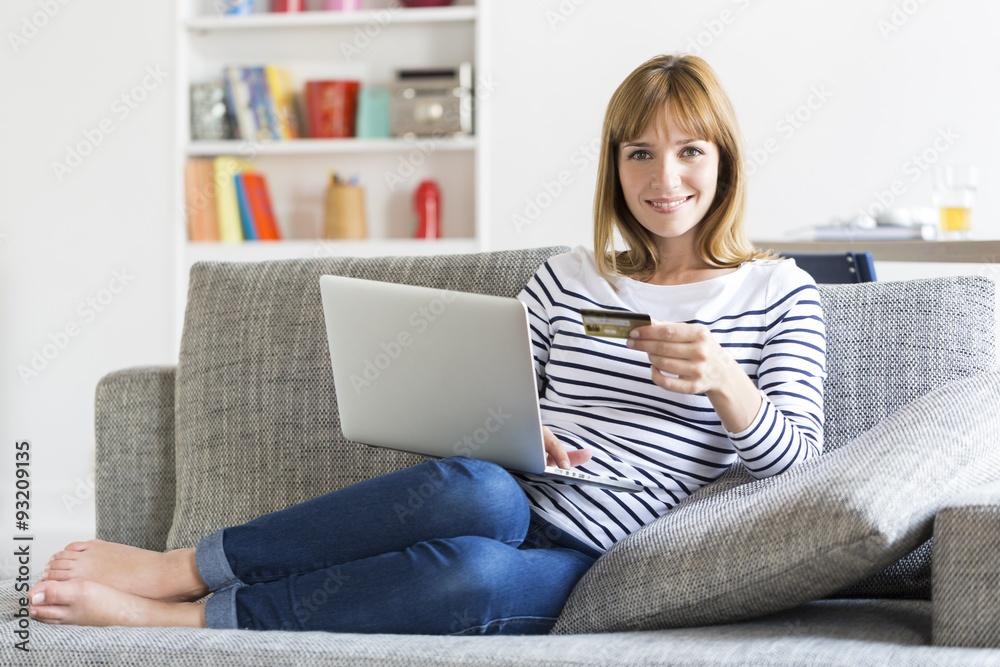 Thirty year old woman shopping using laptop and credit card at home Thirty year old woman shopping using laptop and credit card at home