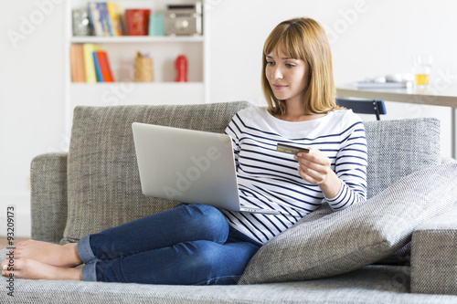 Thirty year old woman shopping using laptop and credit card at home