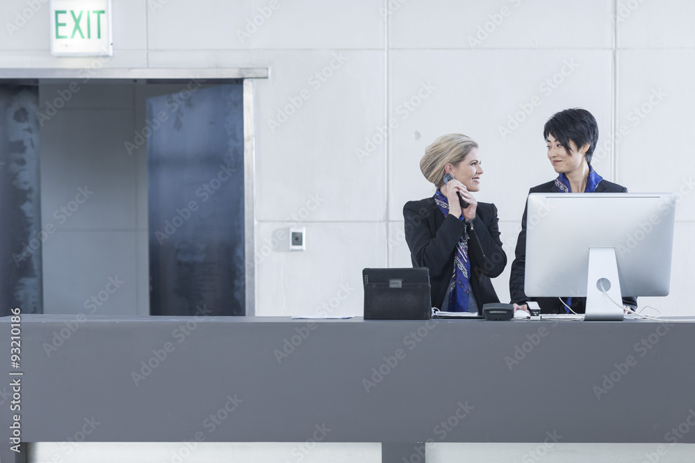 Two women behind reception desk in hotel lobby Two women behind reception desk in hotel lobby