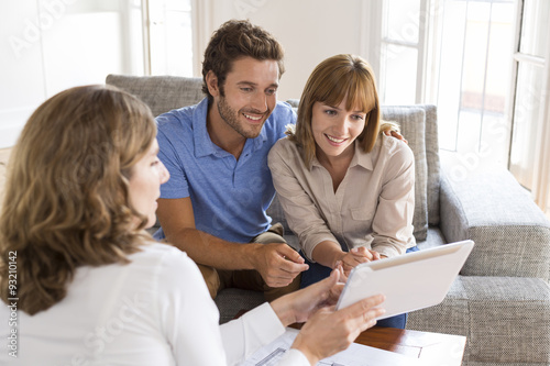 Real-estate agent presenting to a couple a project property on tablet PC