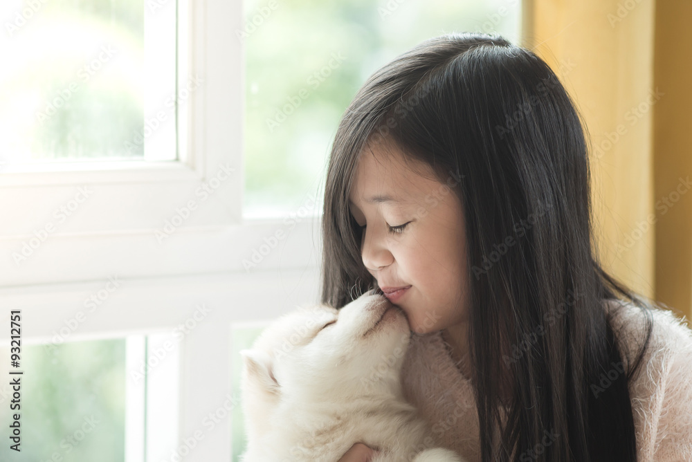Little asian girl kissing a siberian husky puppy