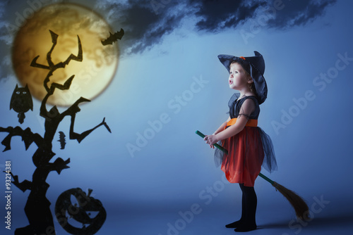 Fototapeta Naklejka Na Ścianę i Meble -  Halloween. Witch child flying on broomstick at sunset night sky.