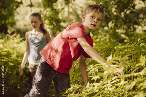 Two children walking through Himalayan Balsam in a forest