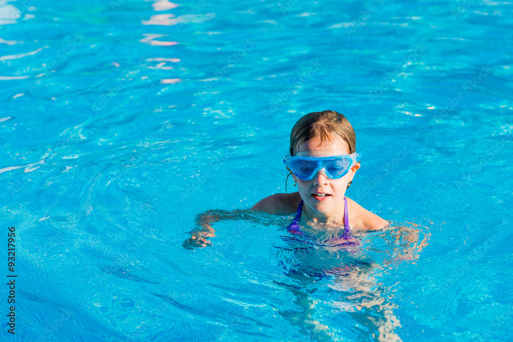 happy girl in blue goggles swimming and snorkeling in the swimming pool