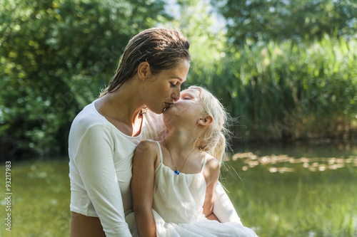 Mother and daughter kissing at a lake photo