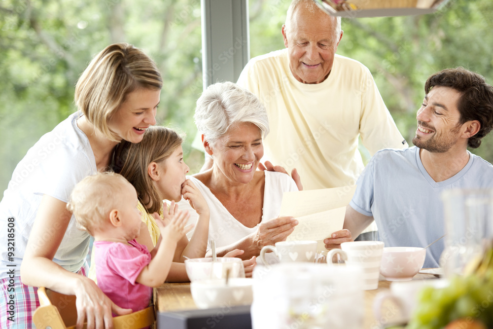 Happy granddaughter with her family reading letter at breakfast table Happy granddaughter with her family reading letter at breakfast table