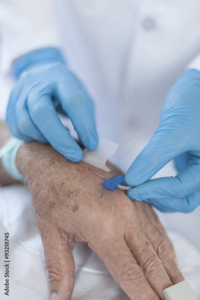 Nurse inserting IV needle in patients hand Nurse inserting IV needle in patients hand