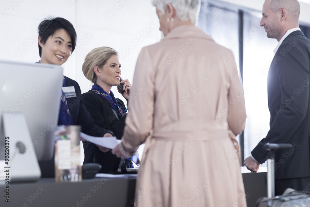 Two women behind reception desk in hotel lobby helping guests Two women behind reception desk in hotel lobby helping guests