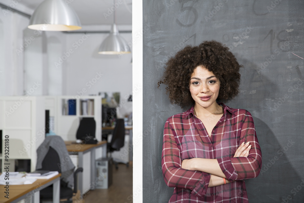 Smiling young woman standing at blackboard in office Smiling young woman standing at blackboard in office