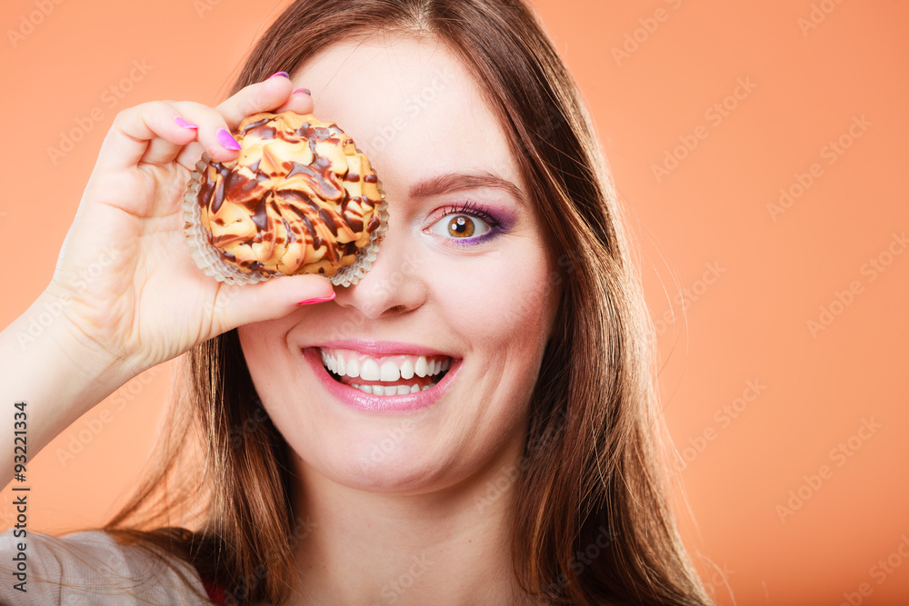 Funny woman holds cake in hand covering her eye