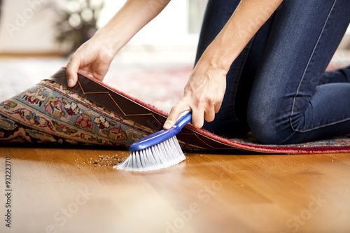Woman sweeping under the carpet