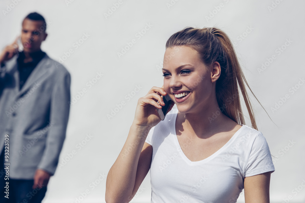 Portrait of smiling young woman telephoning with smartphone in front of white background Portrait of smiling young woman telephoning with smartphone in front of white background