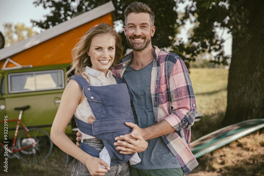 Smiling couple with baby in in front of van in the nature Smiling couple with baby in in front of van in the nature