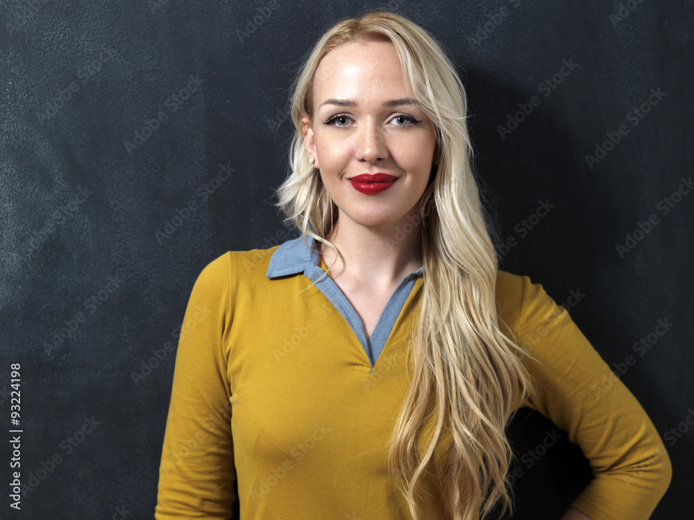 Caucasian woman standing in front of a dark chalkboard. Smiling Caucasian woman standing in front of a dark chalkboard. Smiling