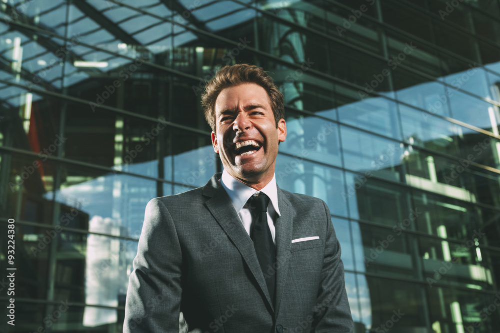 Laughing businessman outside office building Laughing businessman outside office building